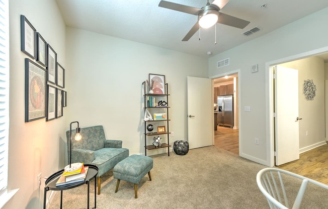 A living room with a sofa, a chair, a coffee table, and a ceiling fan.