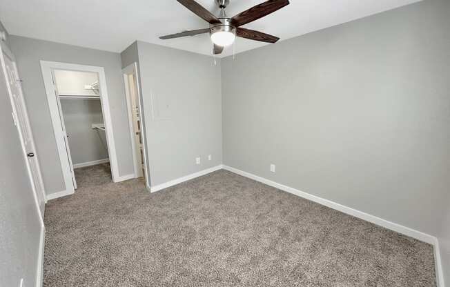 an empty bedroom with a ceiling fan