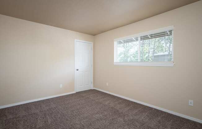 an empty bedroom with carpet and a window