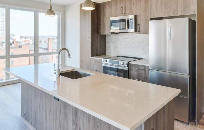 A modern kitchen with a marble countertop and stainless steel appliances.