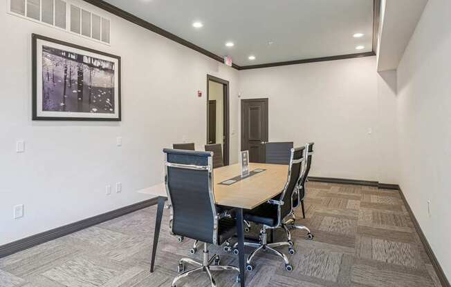 A conference room with a table and chairs and a framed picture on the wall.
