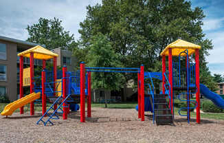 A playground with a blue and yellow slide and a red and yellow structure.