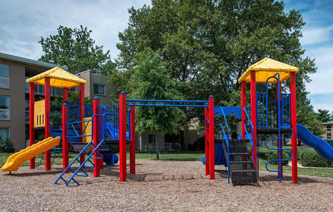 A playground with a blue and yellow slide and a red and yellow structure.