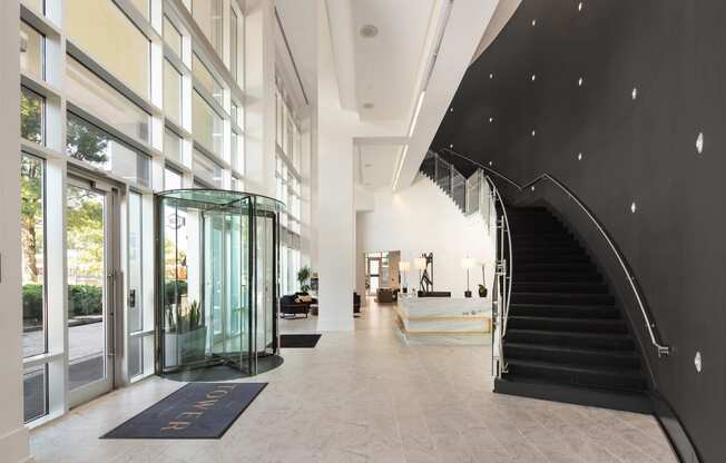 a large lobby with a black spiral staircase and glass doors