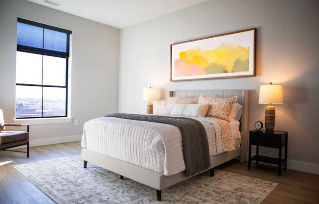 A bedroom with a large bed and a painting on the wall.