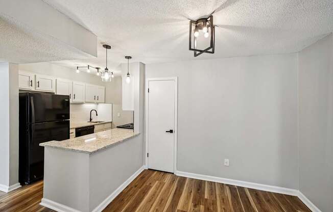 A kitchen with a black refrigerator and white cabinets.