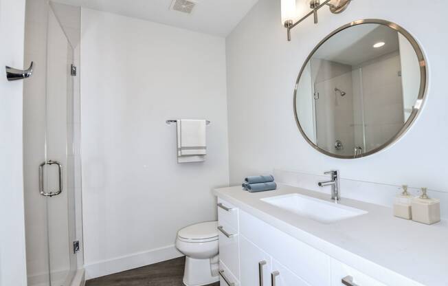 a bathroom with a white sink and toilet next to a shower with a glass door