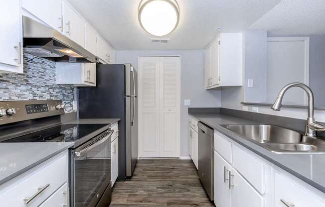 A kitchen with white cabinets and a black refrigerator.