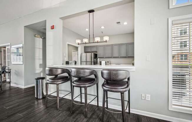 A kitchen with a bar area and three bar stools.