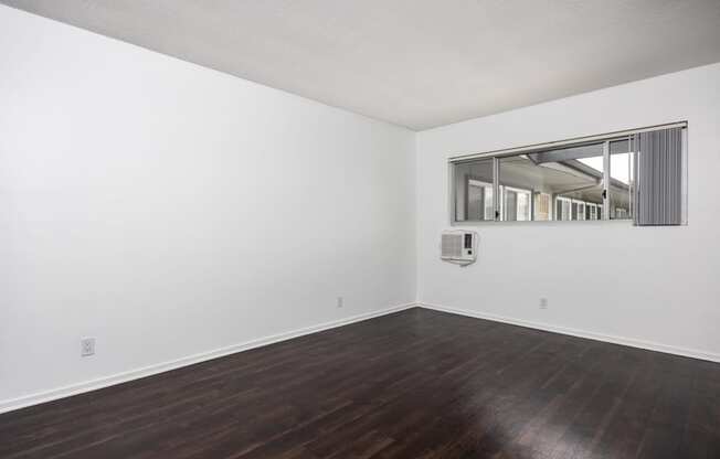 an empty room with white walls and wood floors and a window