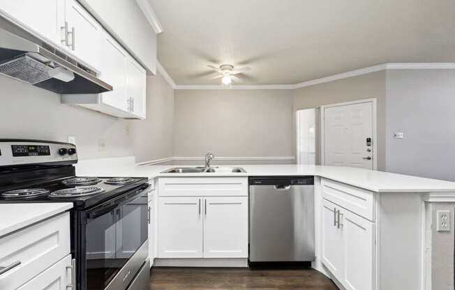 A modern kitchen with white cabinets and a black stove top.
