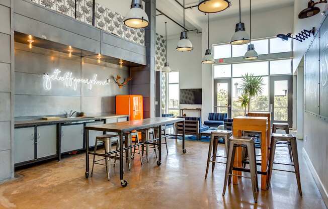 A modern kitchen with a bar area and a neon sign that says "Coffee & Tea".