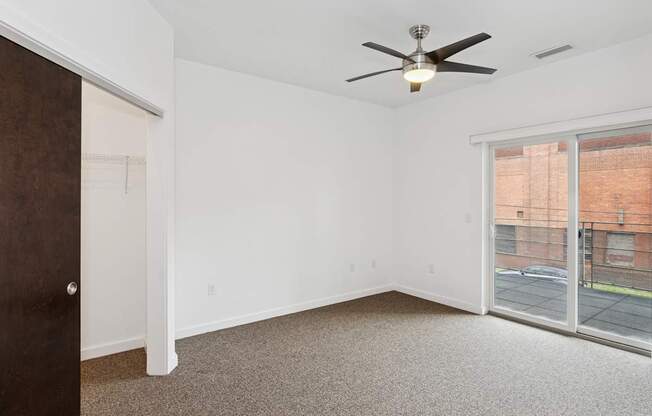 A room with a ceiling fan and a sliding glass door.