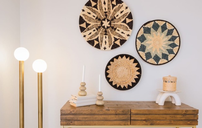 a wooden dresser with three woven wall art on the wall above it