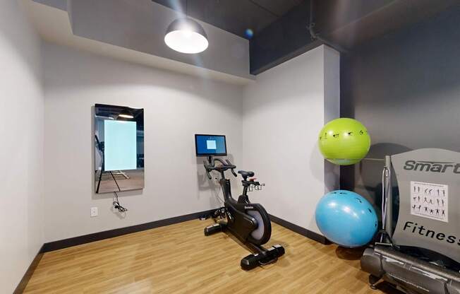 A room with a wooden floor and a wall-mounted TV.