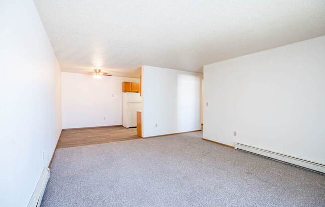 A room with a carpeted floor and a ceiling fan. Fargo, ND Country Edge Apartments