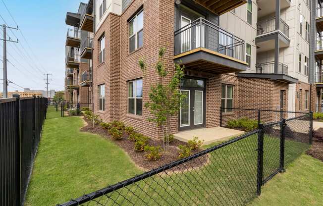an apartment building with a lawn and a fence in front of it