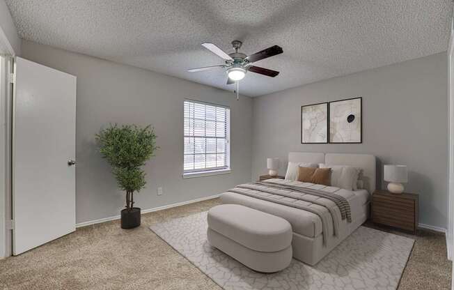 A bedroom with a large bed and a ceiling fan.