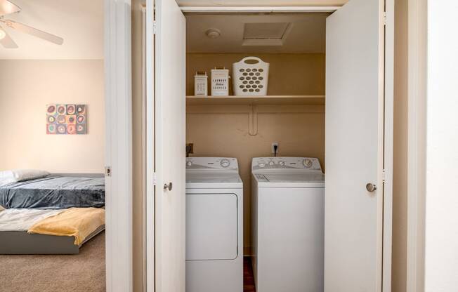 a bedroom with a washer and dryer and a closet with a bed