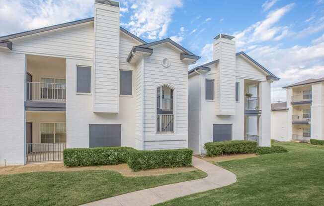 a white apartment building with a sidewalk in front of it