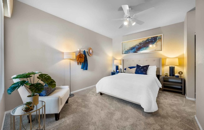 A bedroom with a white bed and a painting on the wall.