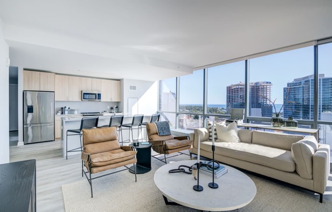 a living room with a view of a kitchen and a large window