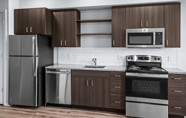 Modern kitchen with Stainless steel appliances, granite countertops, and durable wood-style plank flooring