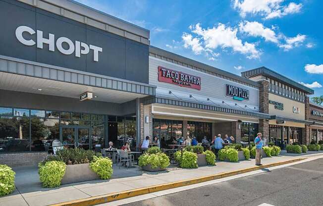 a grocery store with people sitting outside of it on a sidewalk