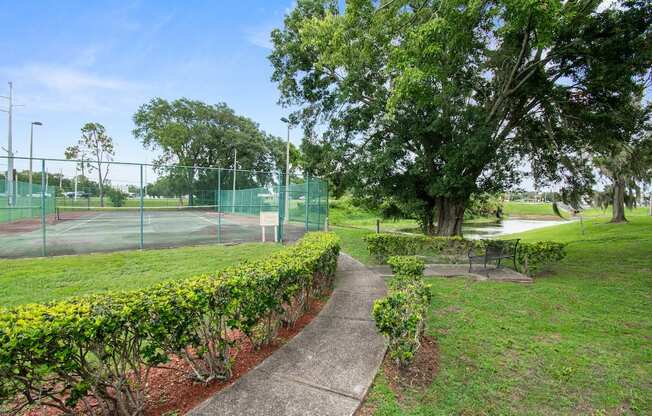 a path leading to a tennis court in a park