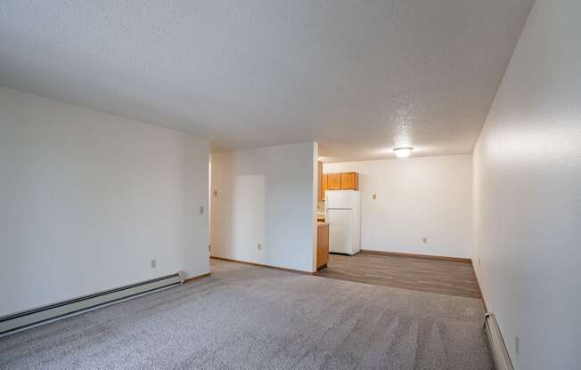 the living room and kitchen of an apartment with white walls and carpet. Fargo, ND  Prairie Park Apartments