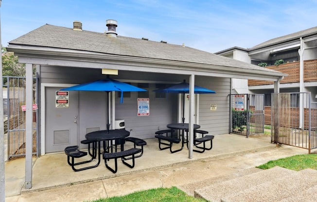 a patio with tables and umbrellas outside of a house