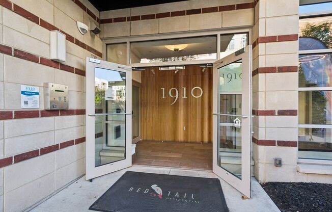 the entrance to a building with an open door and a rug in front of it