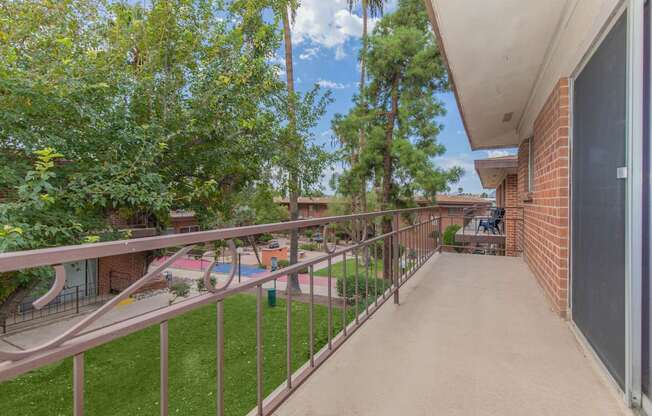 A balcony with a metal railing and a concrete floor.