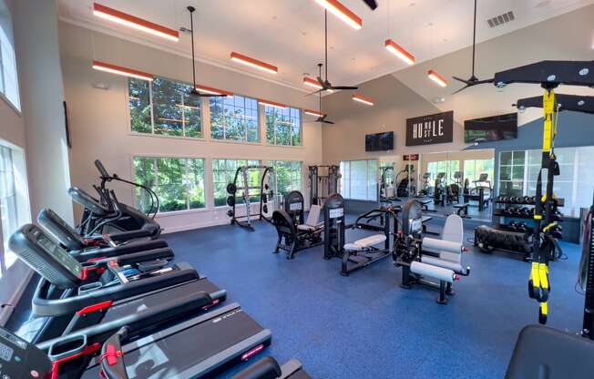 a large fitness room with cardio equipment and windows