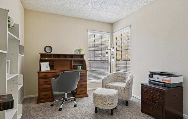 A room with a desk, chair, and printer.