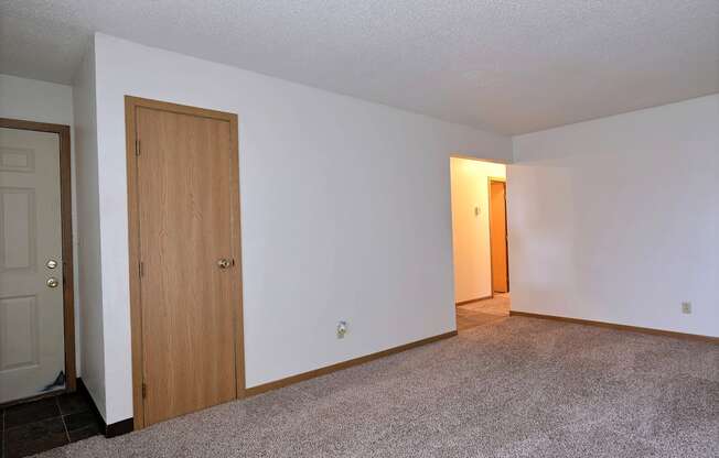 A living room of an empty apartment with a door to the hallway at Parkwest Gardens, 58078 