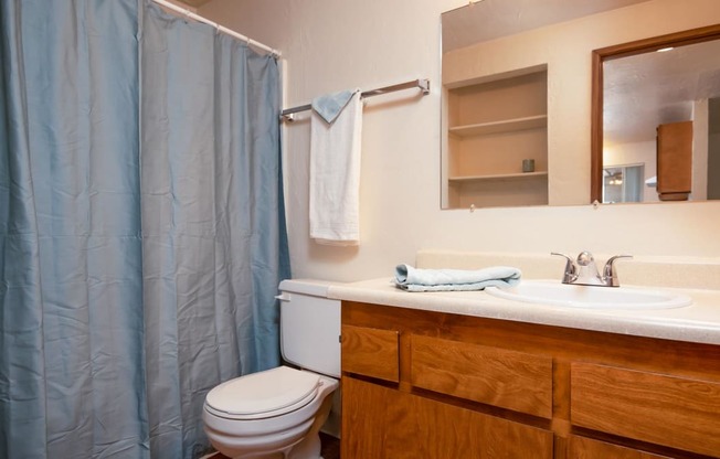 Broadway Center | Bathroom with Wood Cabinetry and Large Mirror