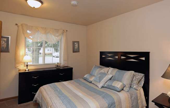 a bedroom with a bed and a dresser and a window and overhead light