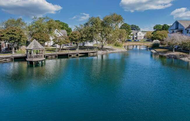 a body of water with a bridge and houses in the background