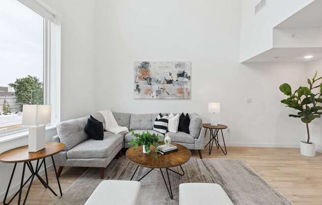 A living room with a grey couch, a coffee table, and a painting on the wall.