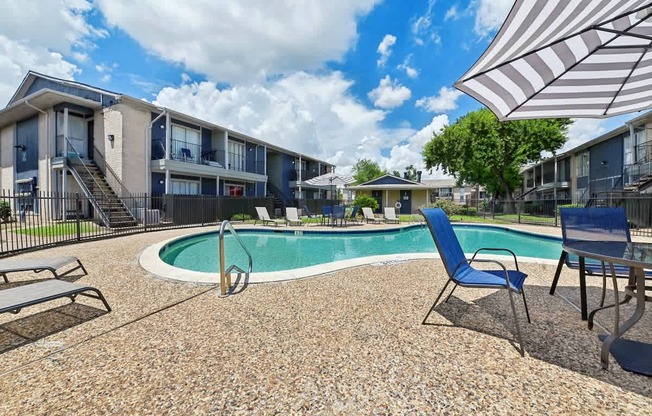A pool surrounded by chairs and umbrellas in a residential area.