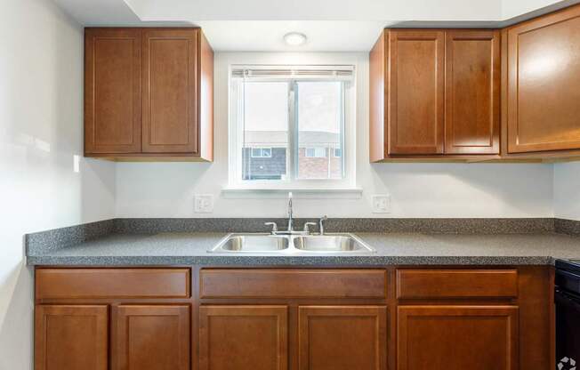 an empty kitchen with wooden cabinets and a window