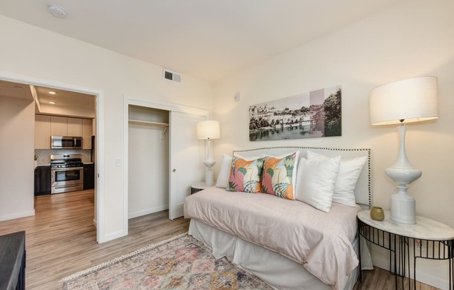 Bedroom with daybed, closet doors open to show available space, area rug and wall art above the bed at Morgan Ranch Apartments, Morgan Hill, 95037