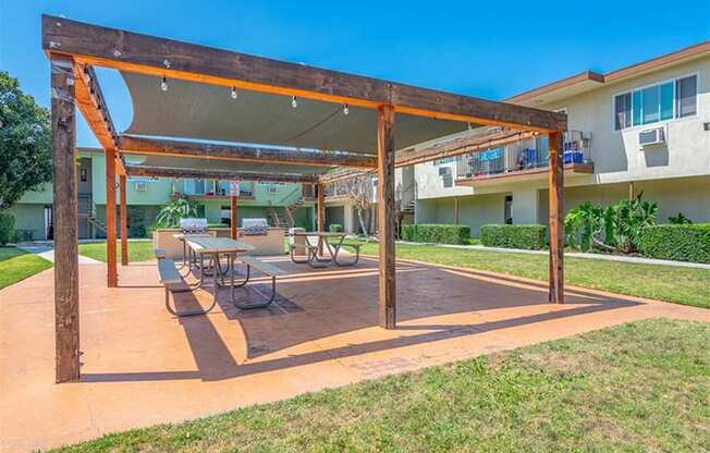 a patio with a table and chairs under a wooden structure