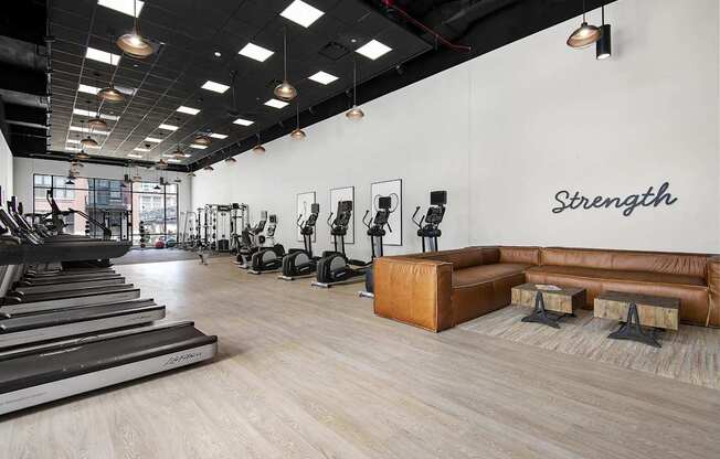 A gym with treadmills, weights, and a bench with the word "Strength" on the wall.