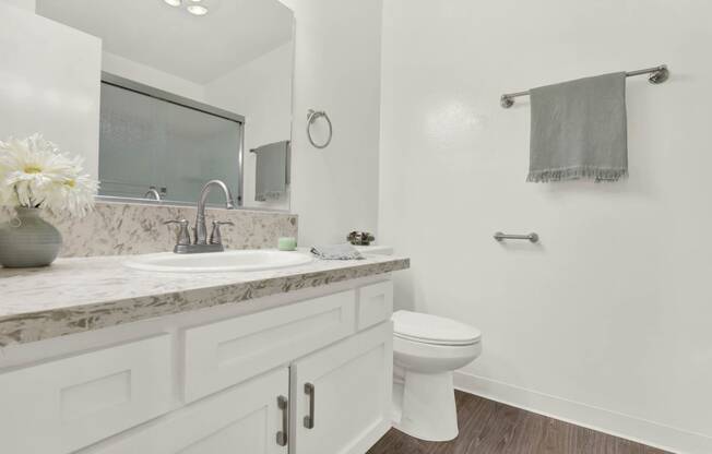 a white bathroom with a sink and a toilet  at Willow Tree Apartments, Torrance, CA