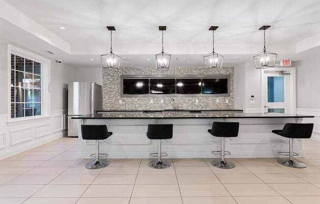 A modern kitchen with a bar area and black stools.