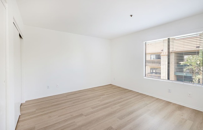 a bedroom with hardwood floors and a large window