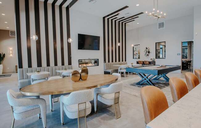 A modern clubhouse with cafe style seating, bar chair, and a pool table.