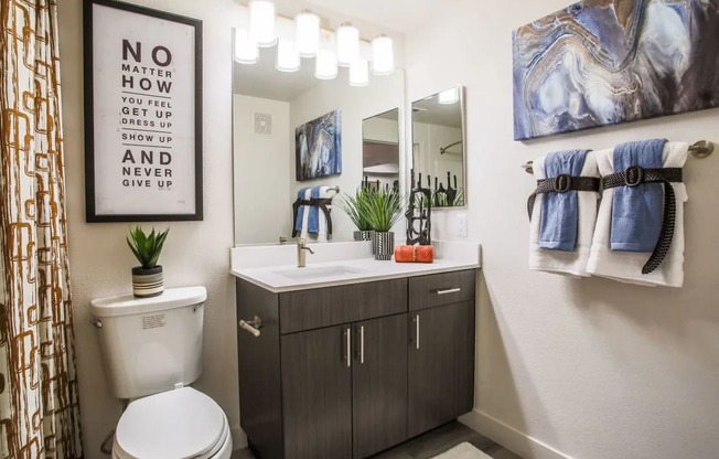 A bathroom with a toilet, sink, and a poster on the wall.